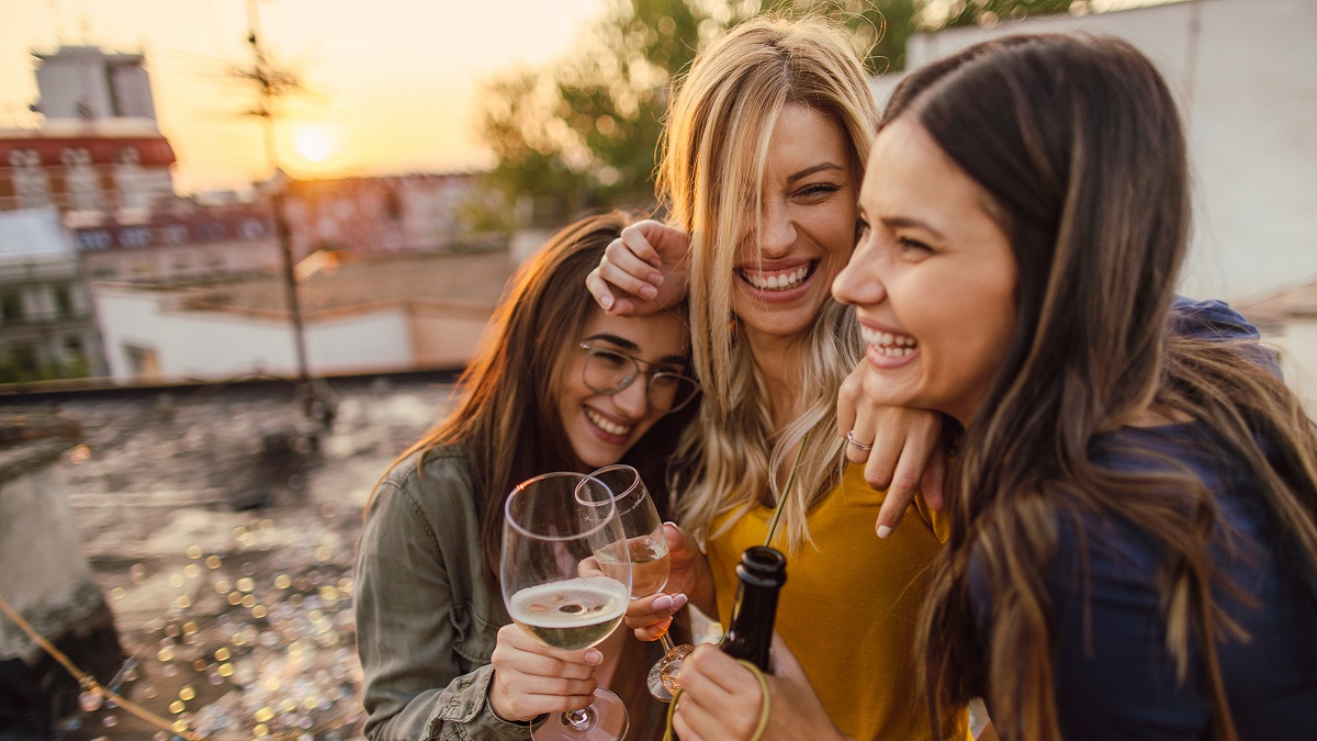 Grupo de chicas festejando con alcohol con un estado de ánimo divertido.